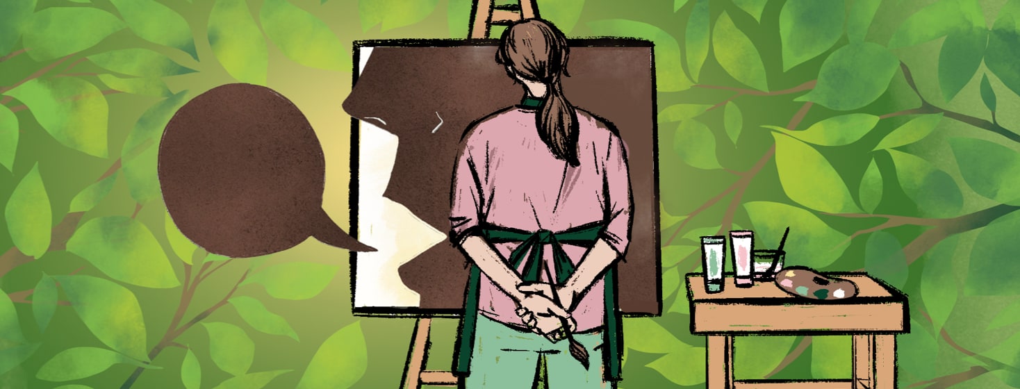 A woman stands outside, paintbrush in one hand as she stands in front of a painted canvas that shows a silhouette of a person speaking.